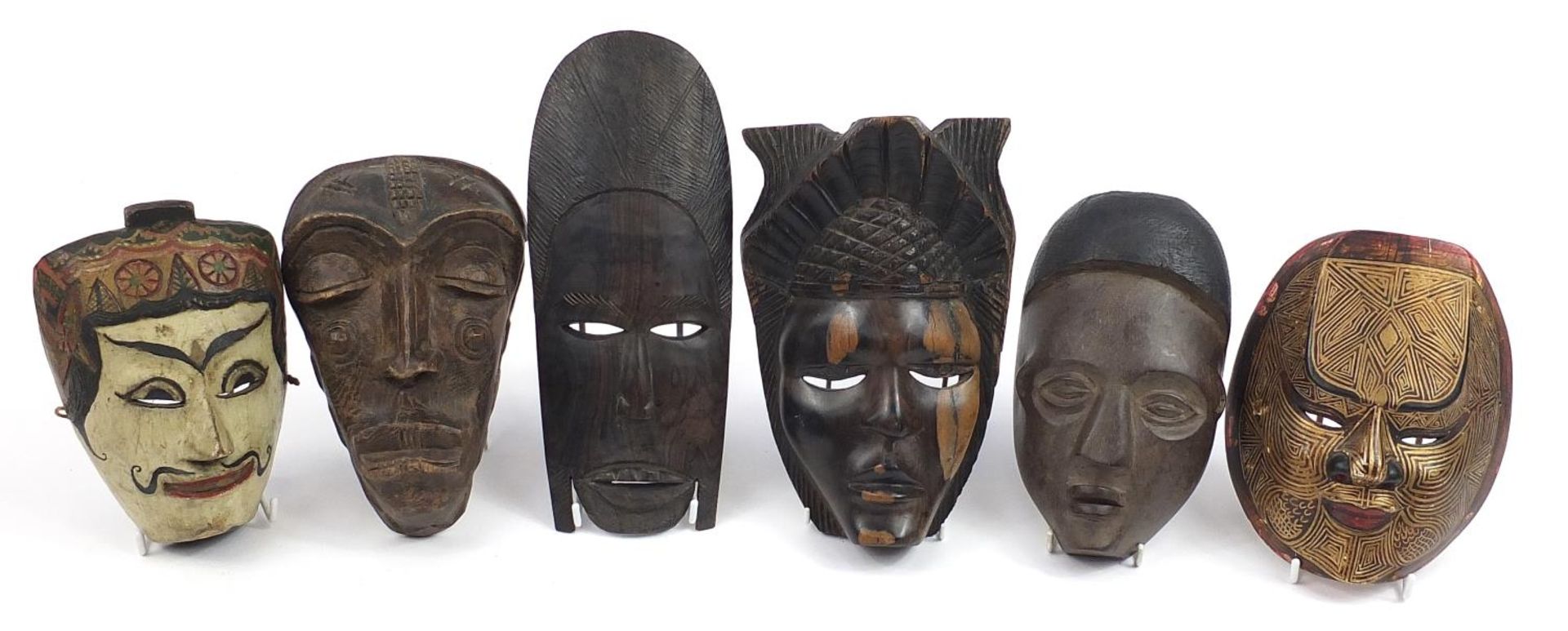 Six tribal interest carved wood face masks, the largest 31cm high