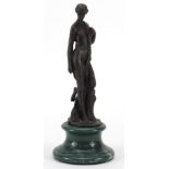 Patinated bronze study of a standing semi nude female raised on a circular green marble base, 24cm