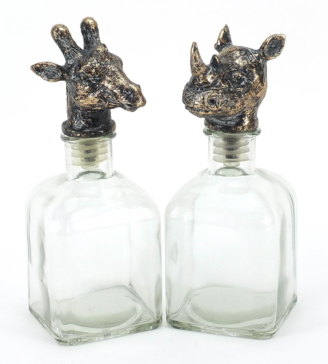 Pair of glass decanters with bronzed rhinoceros and giraffe head stoppers, the largest 24.5cm high