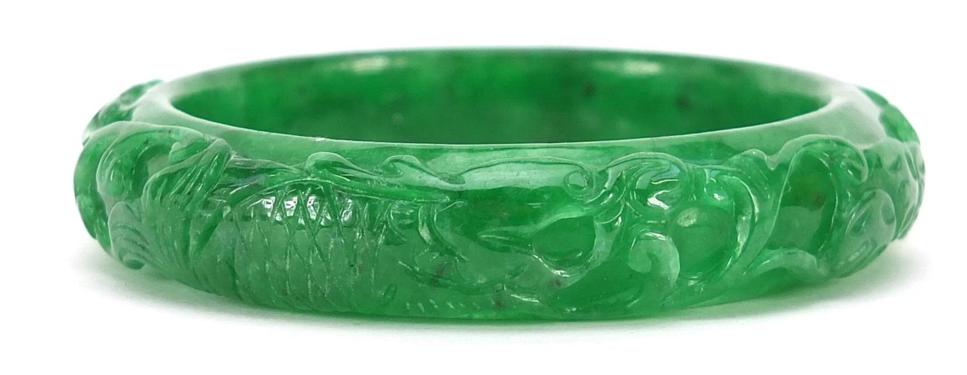 Chinese green jade bangle carved with a fish amongst aquatic foliage, 7cm in diameter, 56.7g