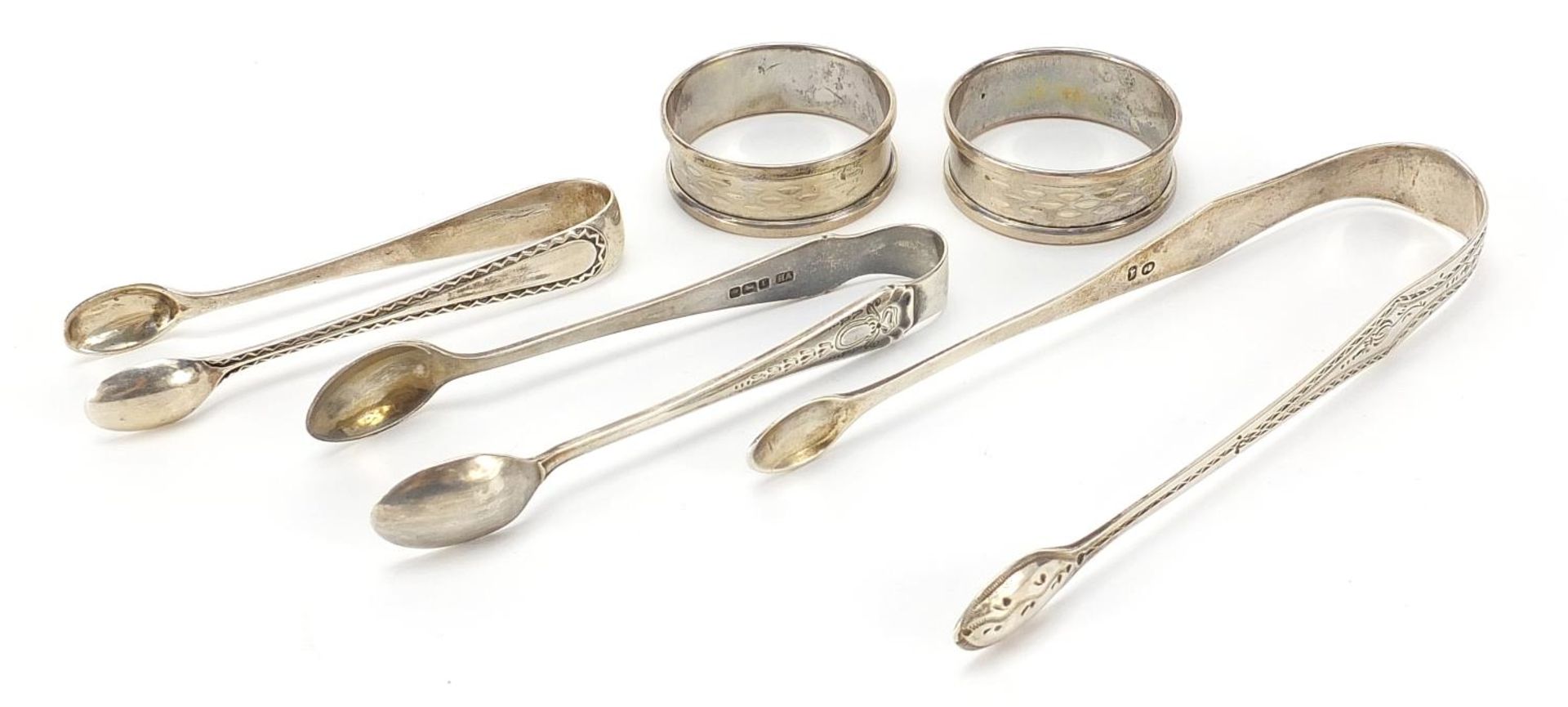 Three pairs of Georgian and later silver sugar tongs and pair of circular silver napkin rings, the