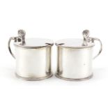 Sydney Bellamy Harman, pair of George V silver mustards with hinged lids and blue glass liners,