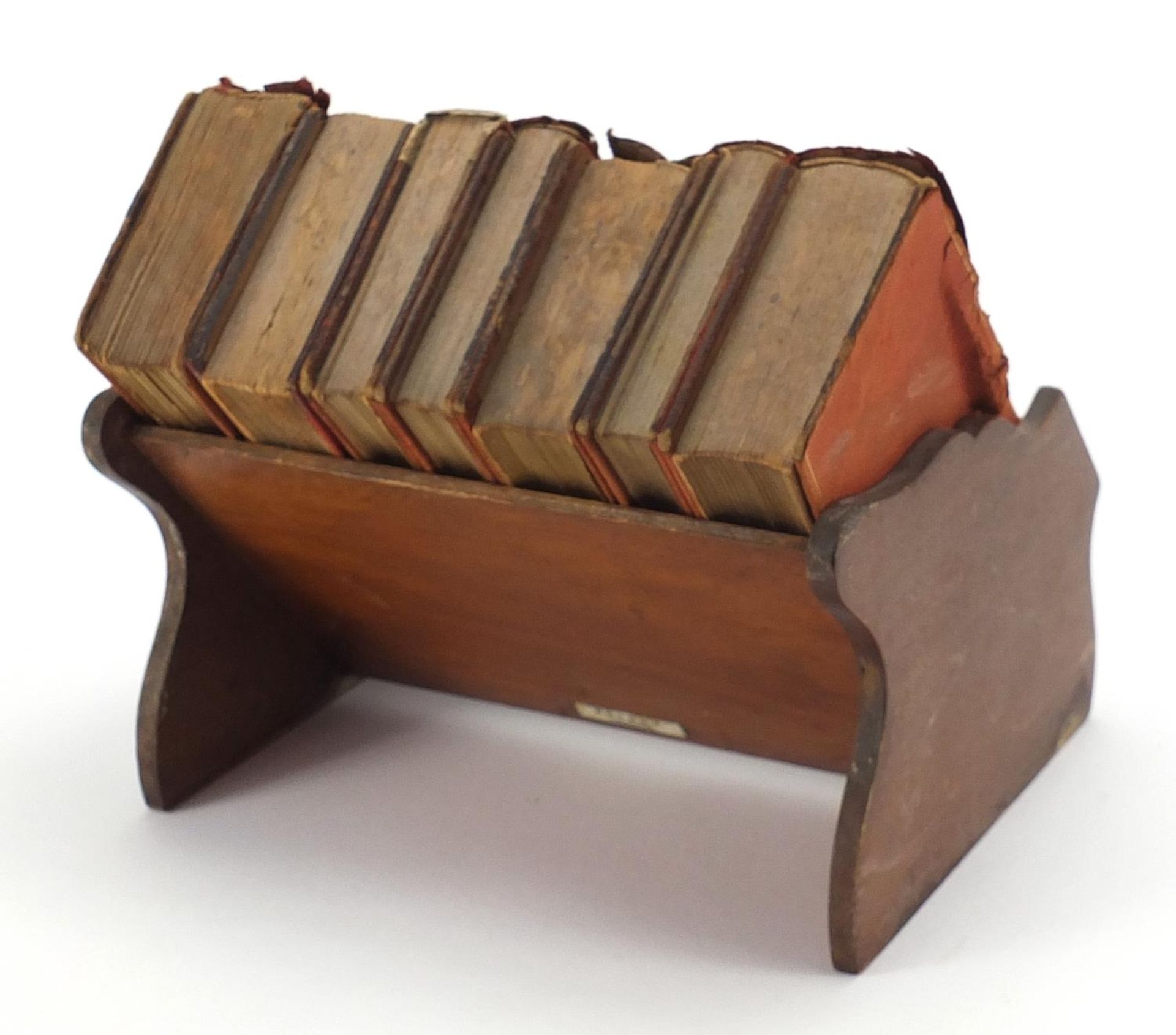 Miniature mahogany bookshelf housing eight books by Asprey of London, 20.5cm wide