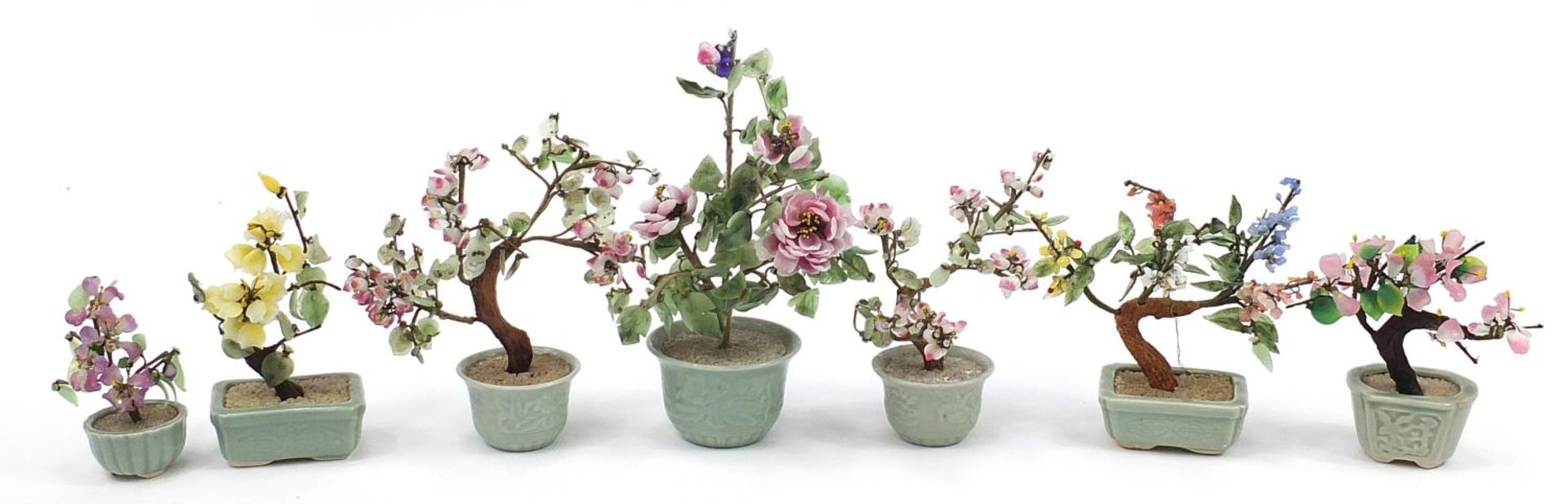 Seven Chinese hardstone bonsai trees with celadon glazed planters, the largest 28cm high