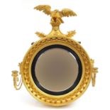 Regency giltwood convex wall mirror with sconces and eagle crest, 75cm high