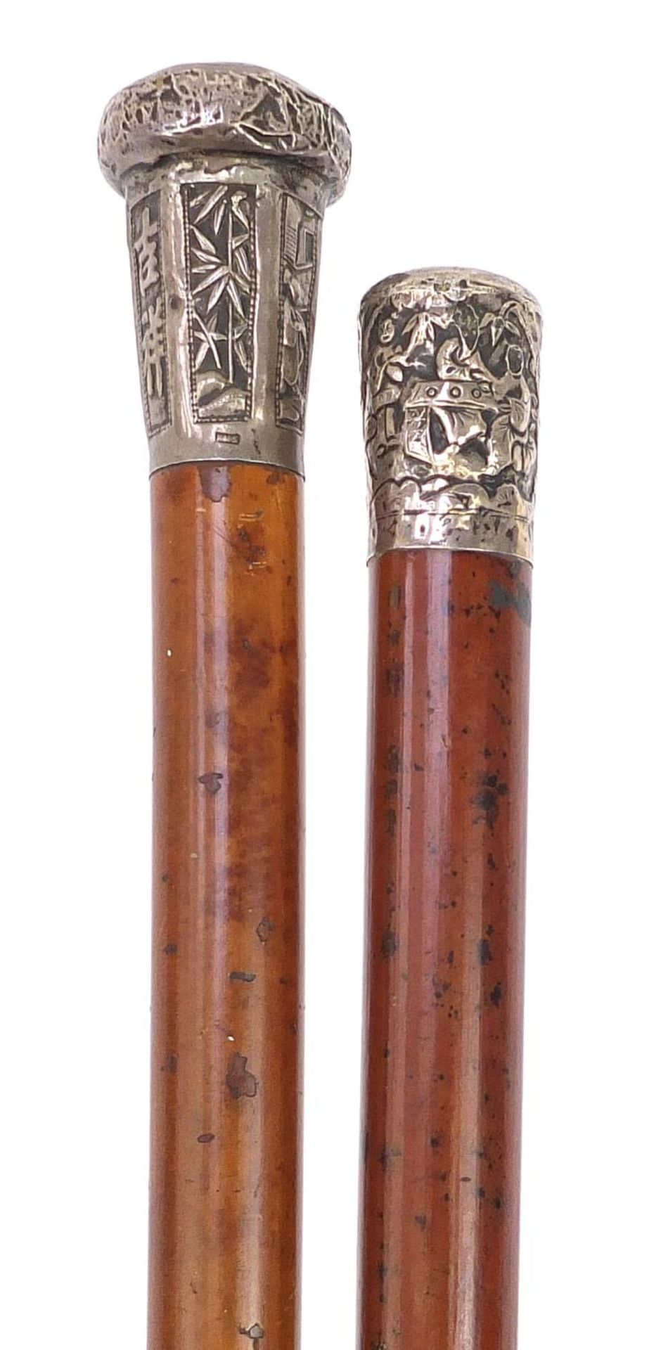 Two malacca walking sticks with Chinese silver pommels embossed with figures and calligraphy, the