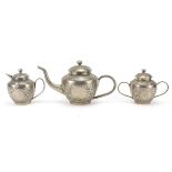 Anglo Indian white metal three piece tea service embossed with flowers and foliage, the teapot