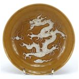 Chinese porcelain dish decorated in low relief with a dragon chasing a flaming pearl amongst clouds,