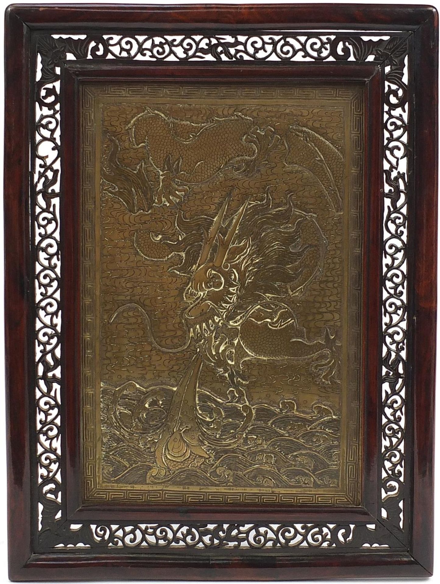Chinese bronze panel decorated with a dragon, housed in a hardwood frame carved with bats, overall
