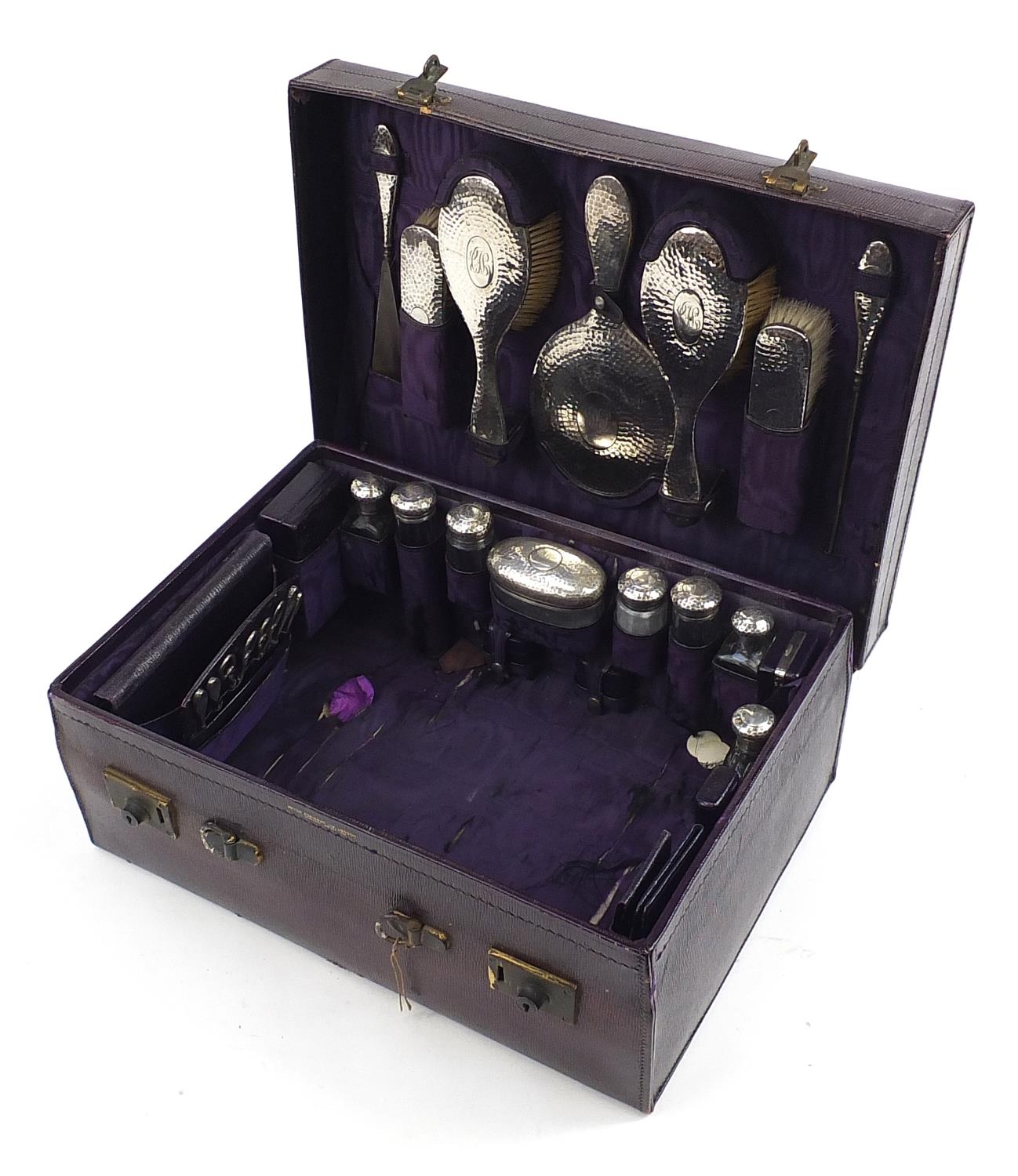 Edwardian purple leather travelling vanity case with silver mounted items including brushes,