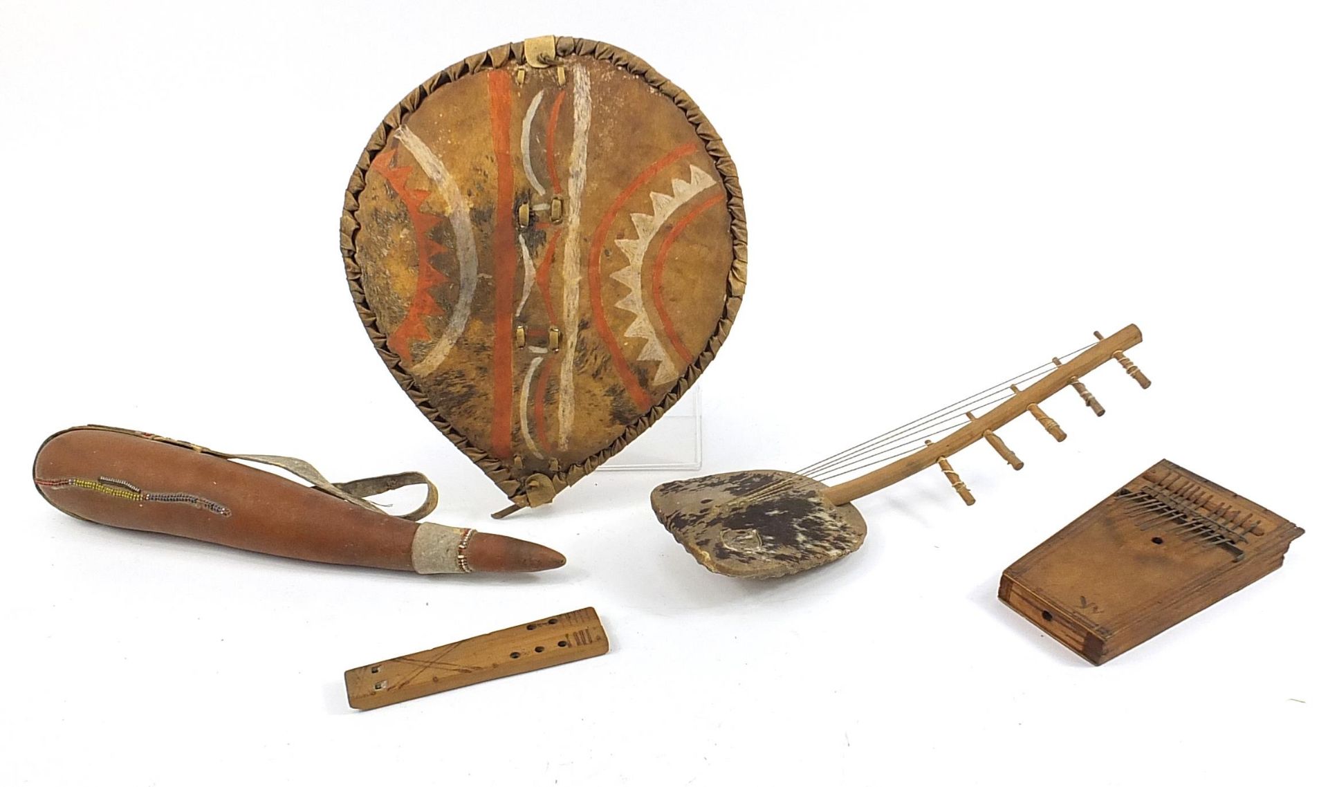 Tribal objects including a hand painted animal hide shield and musical instruments, the largest 50cm