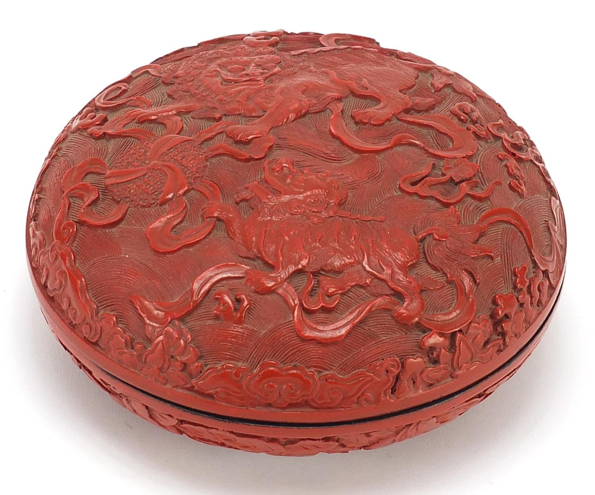 Chinese cinnabar lacquered bun box and cover carved with Foo dogs amongst clouds, 18cm in diameter