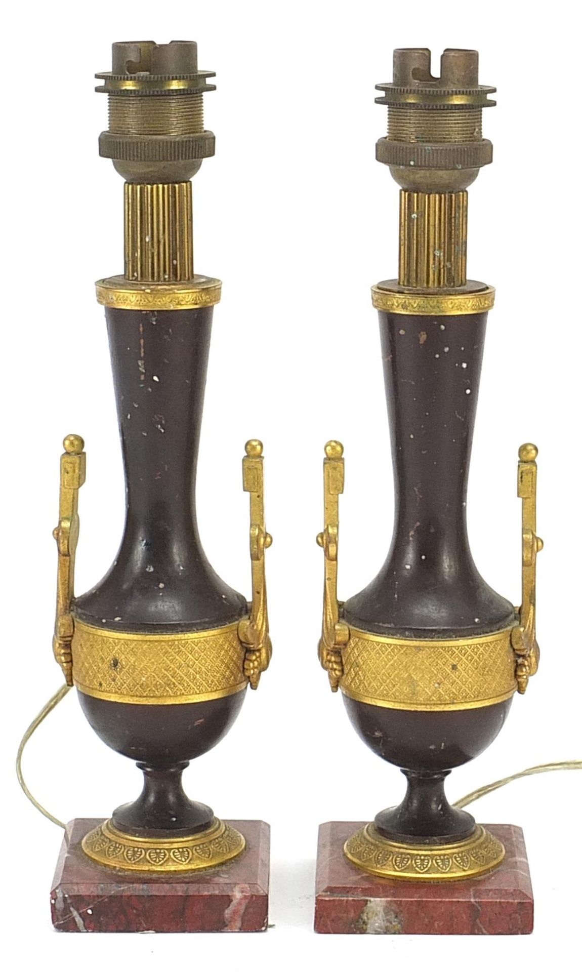 Pair of French patinated bronze and ormolu candlesticks converted to table lamps, each raised on