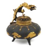 Chinese partially gilt patinated bronze tripod incense burner with pierced lid and dragon handle,