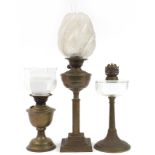 Three Victorian brass oil lamps, two with glass shades, the largest 65cm high