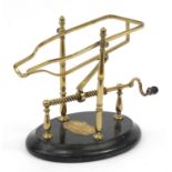 Farrow & Jackson of London & Paris, 19th century brass mechanical wine cradle with an ebonised base,