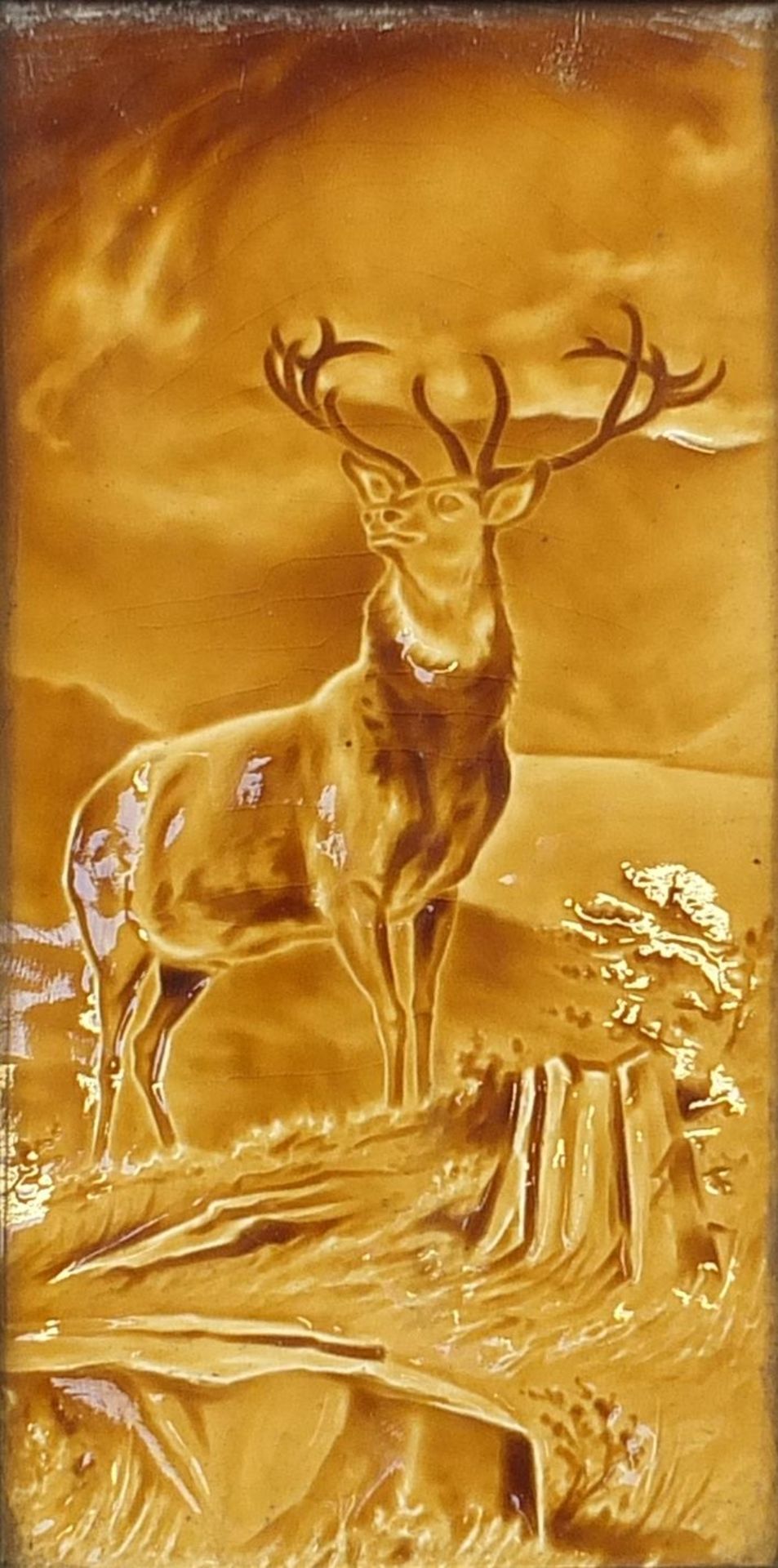 Large Victorian treacle glazed tile hand painted with a stag, framed, the tile 29cm x 14.5cm