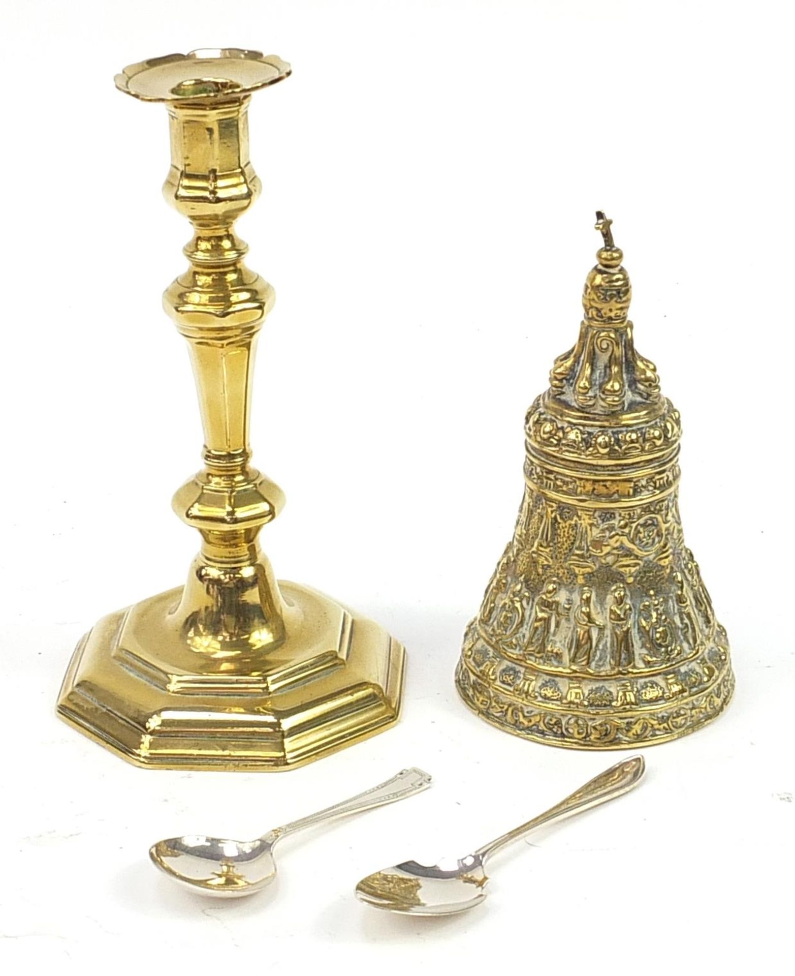 Metalware comprising a heavy gilt brass bell, candlestick and two silver spoons, the largest 23cm