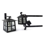 Two black painted wrought metal wall lanterns, the largest 34cm high