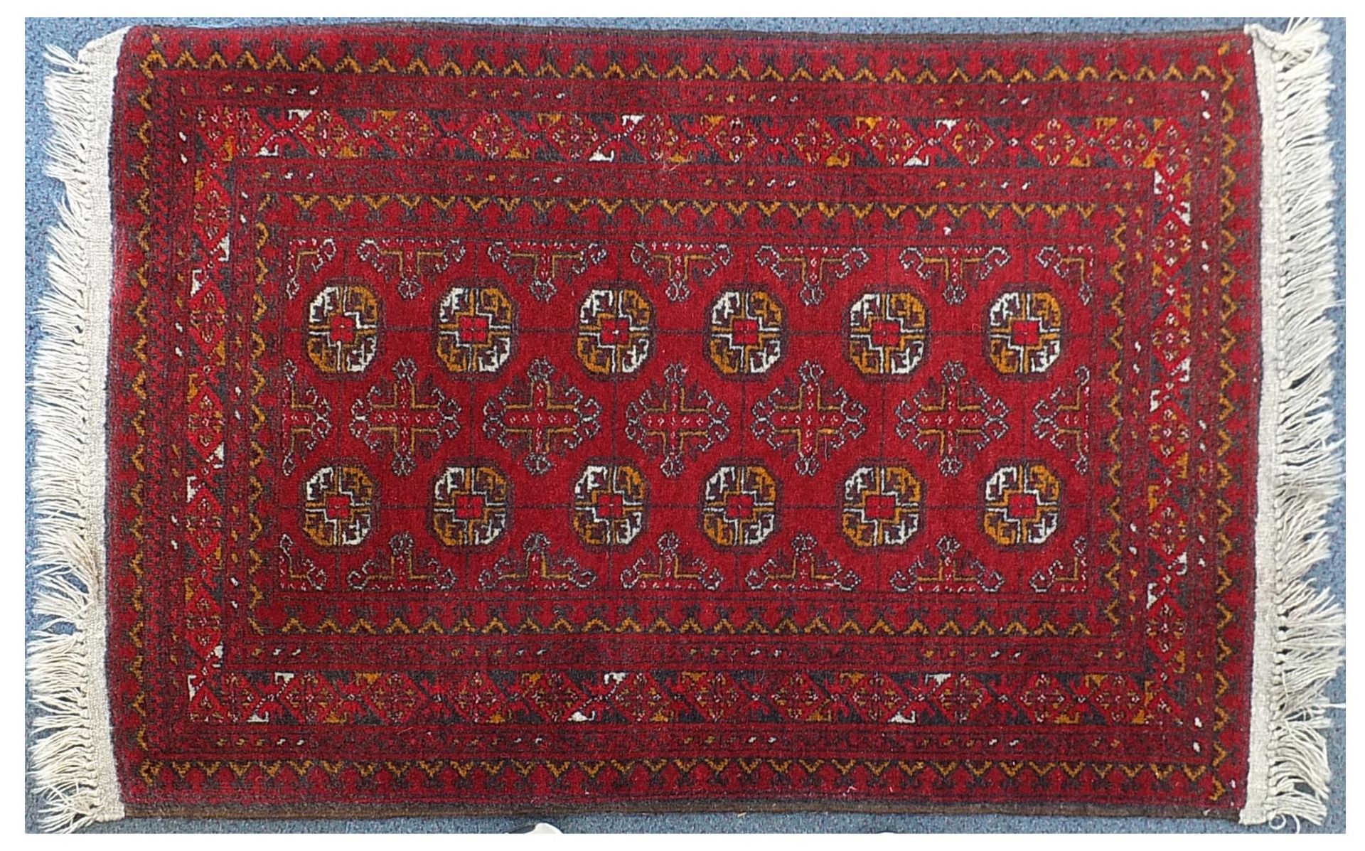 Red ground rug having an all over geometric design, 135cm x 80cm