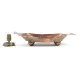 Islamic brass candlestick and a copper four footed dish incised with wild animals and flowers, the