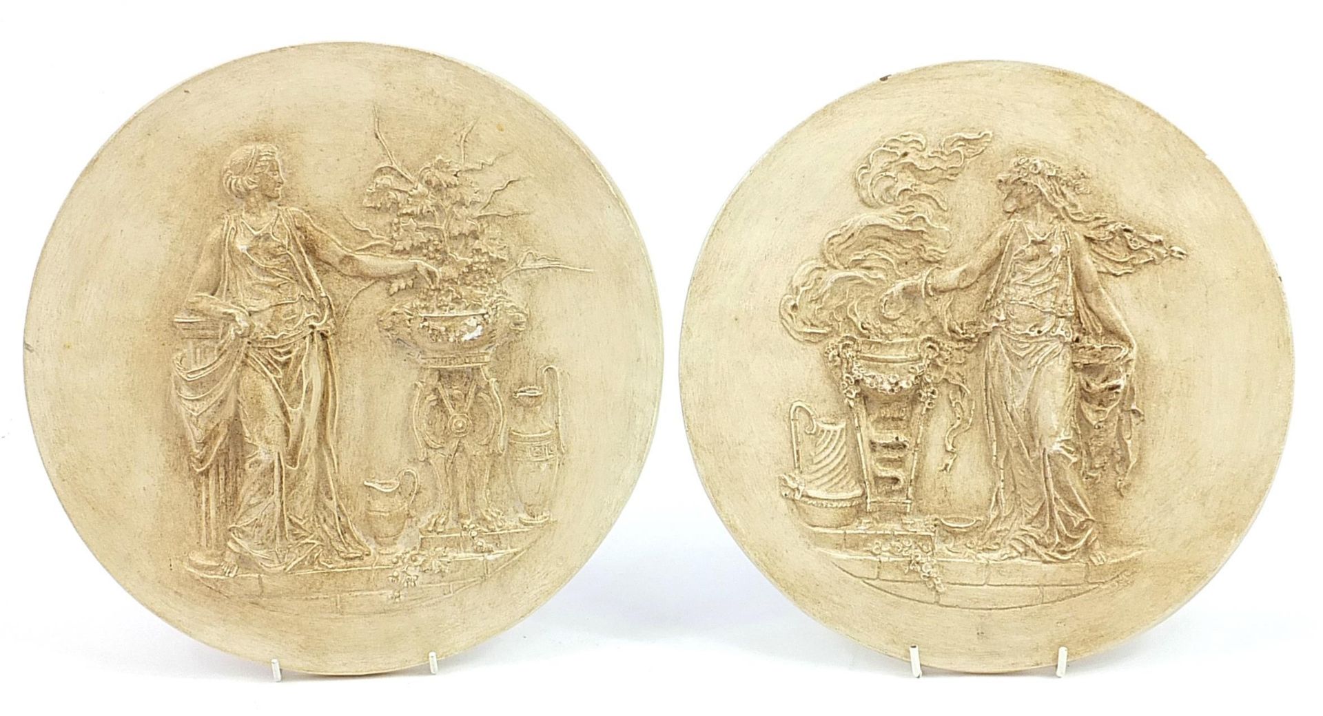 Pair of circular classical wall plaques decorated in relief with Grecian females, each 31cm in