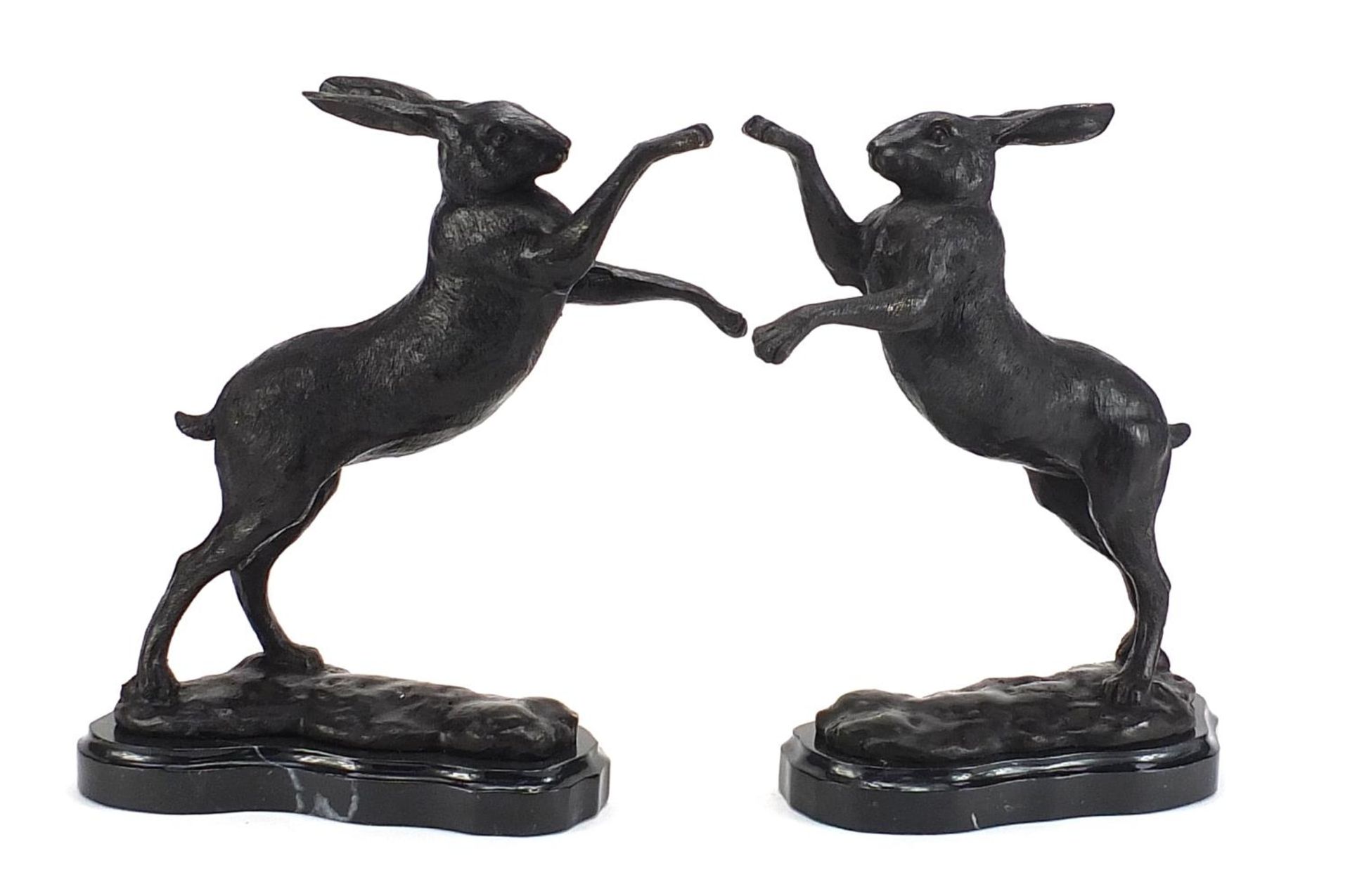Pair of patinated bronze boxing hares raised on shaped marble bases, each 30cm high