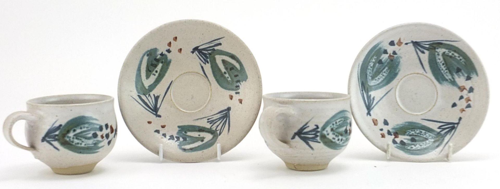 Marianne de Trey, pair of studio pottery cups and saucers hand painted with stylised motifs,