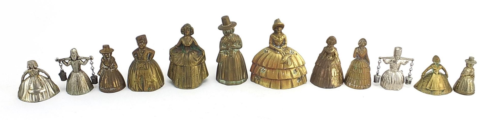 Twelve brass and white metal Crinoline Lady table bells, the largest 10.2cm high