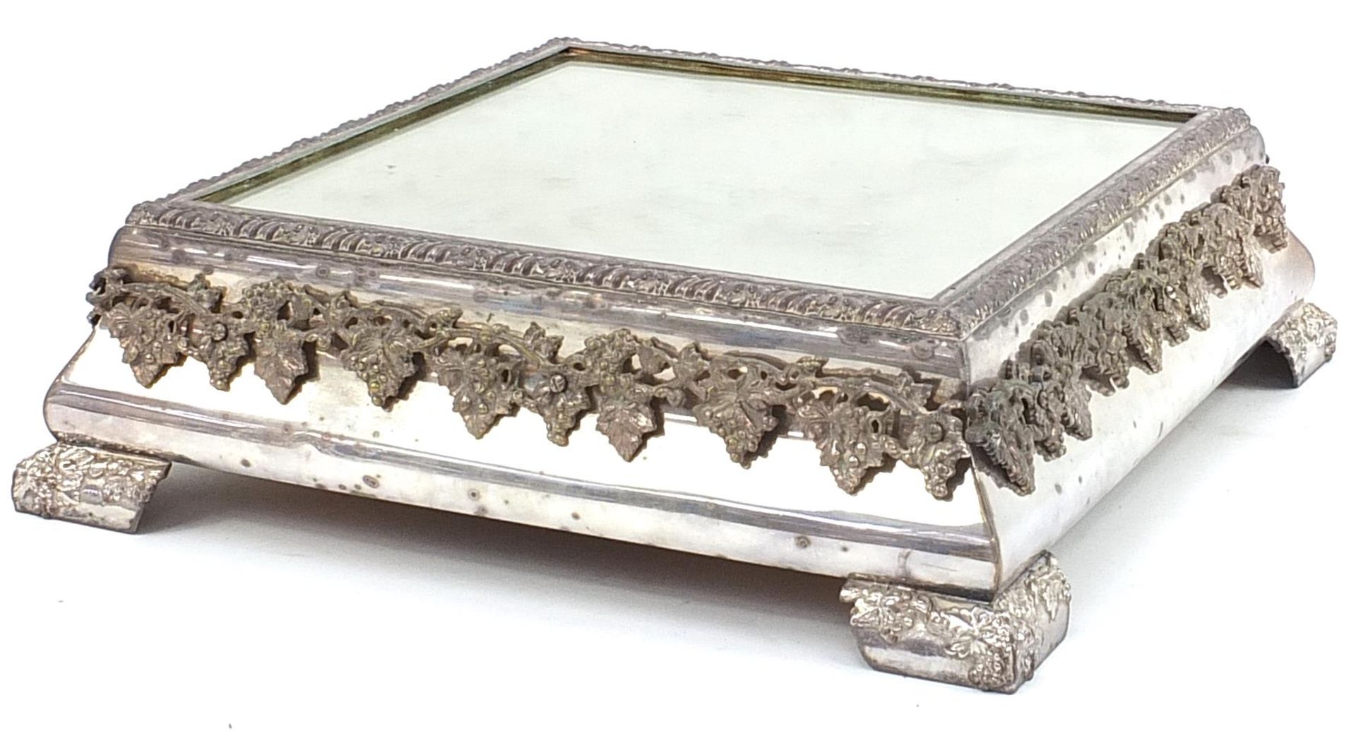 Square silver plated mirrored cake stand relief decorated with grapes on a vine, housed in a painted