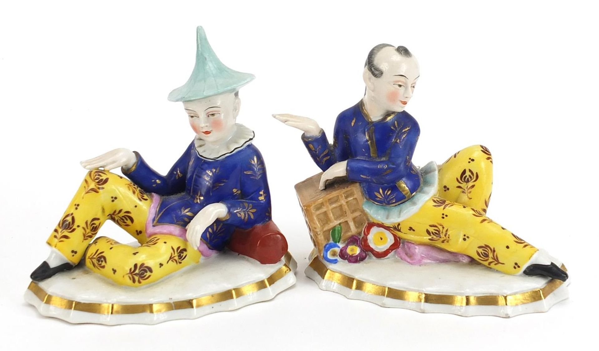 Pair of English porcelain figures of resting Chinese boys, each 14cm wide