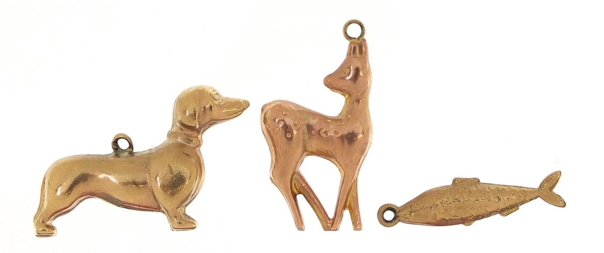 Three 9ct gold charms comprising Dachshund, deer and fish, the largest 2.5cm in length, total 3.8g