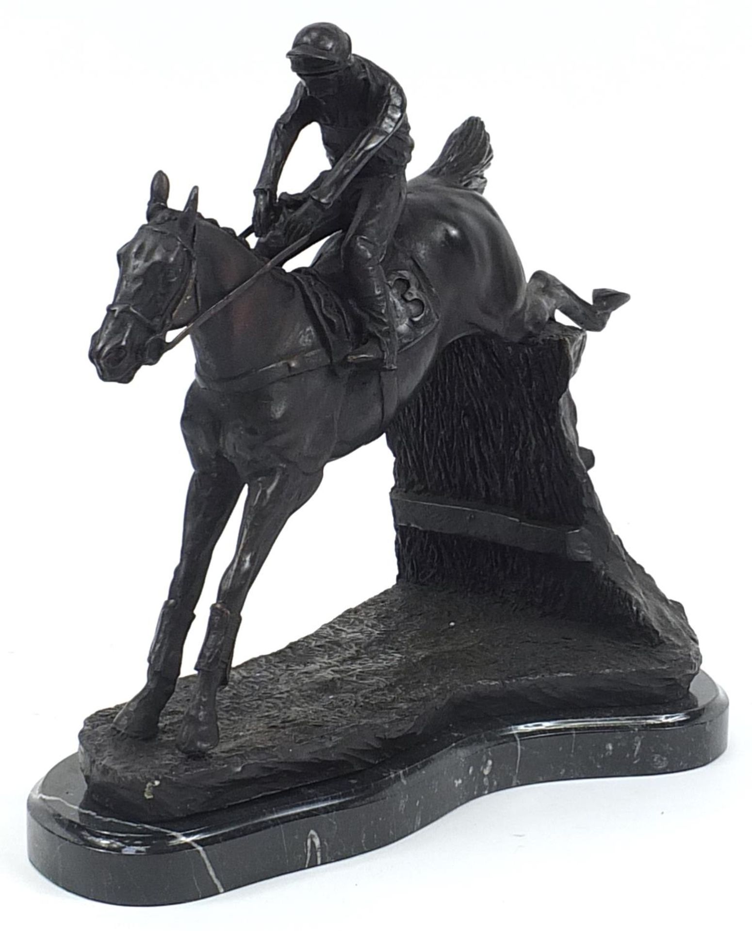 Large patinated bronze jockey on horseback raised on a black marble base, 35cm in length