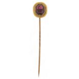 Antique unmarked gold purple stone stickpin, possibly garnet, housed in a velvet and silk lined