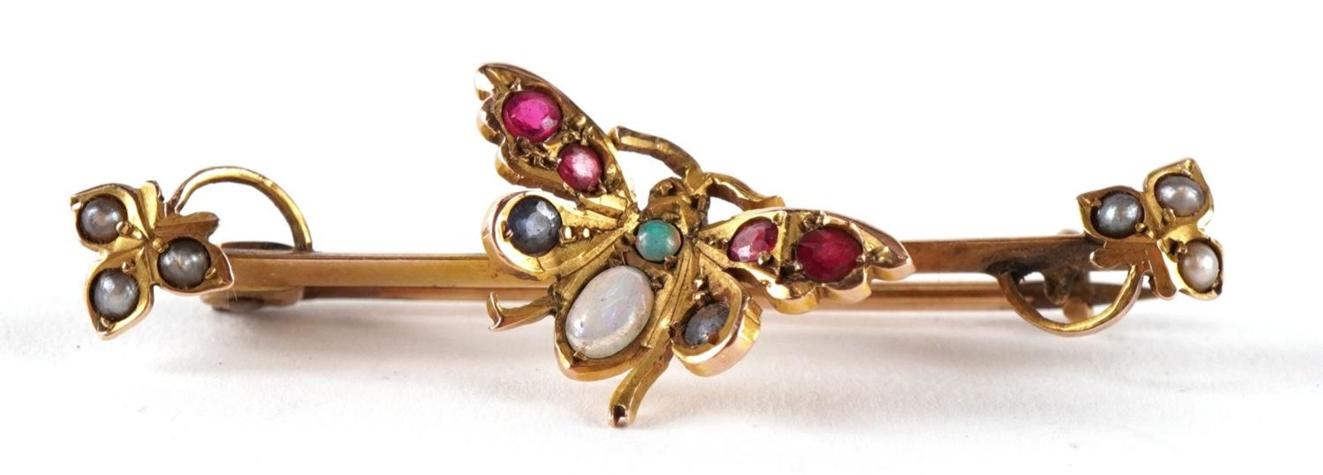 Victorian 9ct gold butterfly brooch set with seed pearls, opals and red stones housed in a tooled
