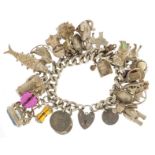 Heavy silver charm bracelet with a selection of mostly silver charms including articulated teddy