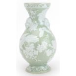 Aesthetic porcelain green glazed vase decorated in relief with masks and birds amongst flowers, 25cm