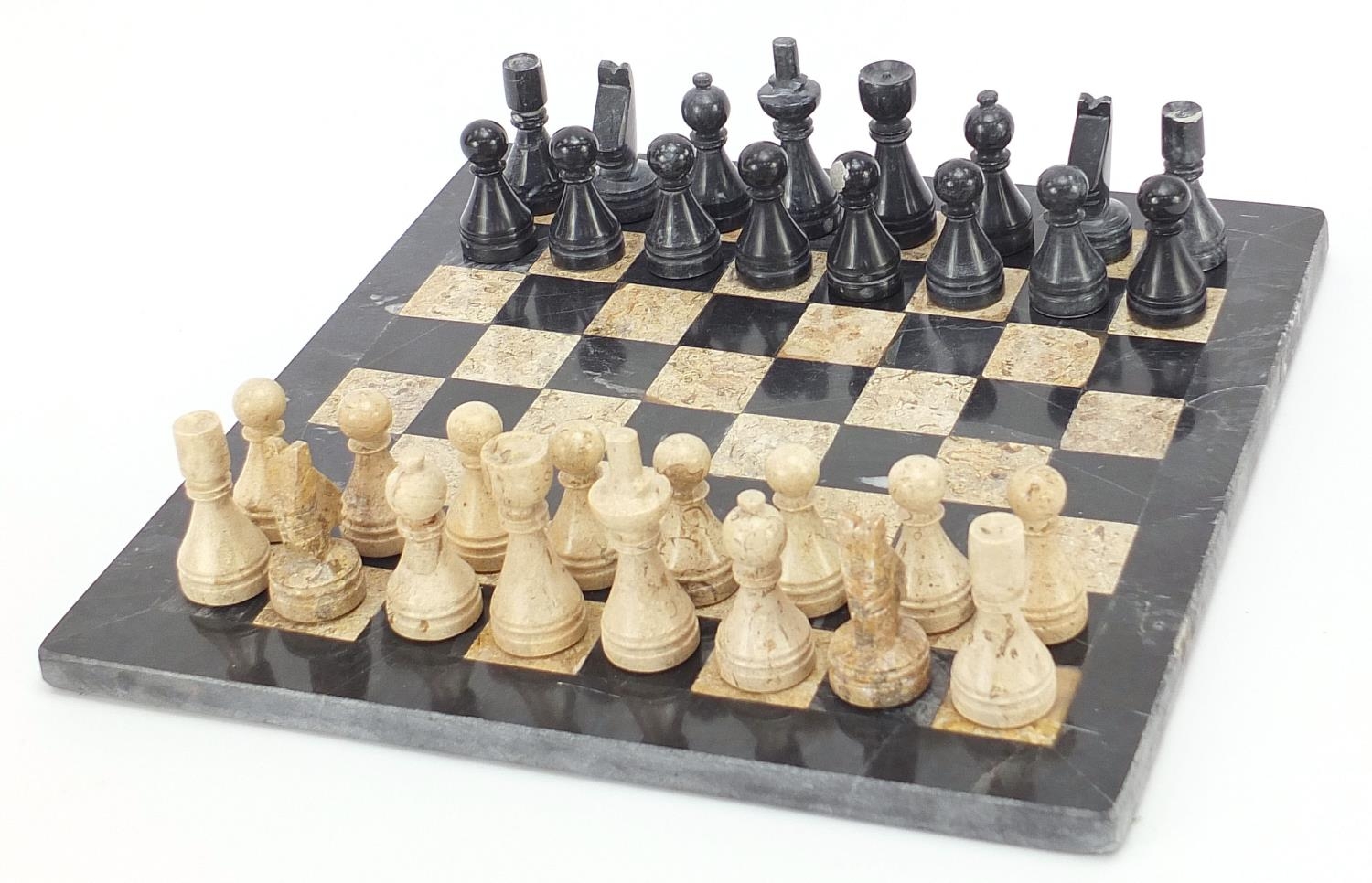 Carved stone chess set with inlaid marble board, the largest pieces each 6.5cm high, the board