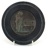 Military interest bronzed plaque with ebonised frame, 13cm in diameter