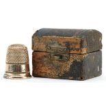 Yellow metal thimble housed in a tooled leather box in the form of a chest, the thimble 2.1cm high