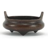 Chinese patinated bronze censer with twin handles raised on three feet, character marks to the base,