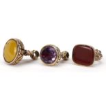 Three yellow metal fobs, one set with a carnelian, the largest 3.5cm high, 44.5g