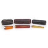 Three amber coloured cheroot cigarette holders with fitted cases including one with 9ct gold mount