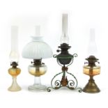 Four antique and later oil lamps, three with glass reservoirs including one with a painted wrought