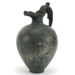 Antique patinated bronze spouted vessel with figural handle, 19.5cm high