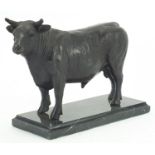 Patinated bronze bull raised on a rectangular black marble base, 24cm in length
