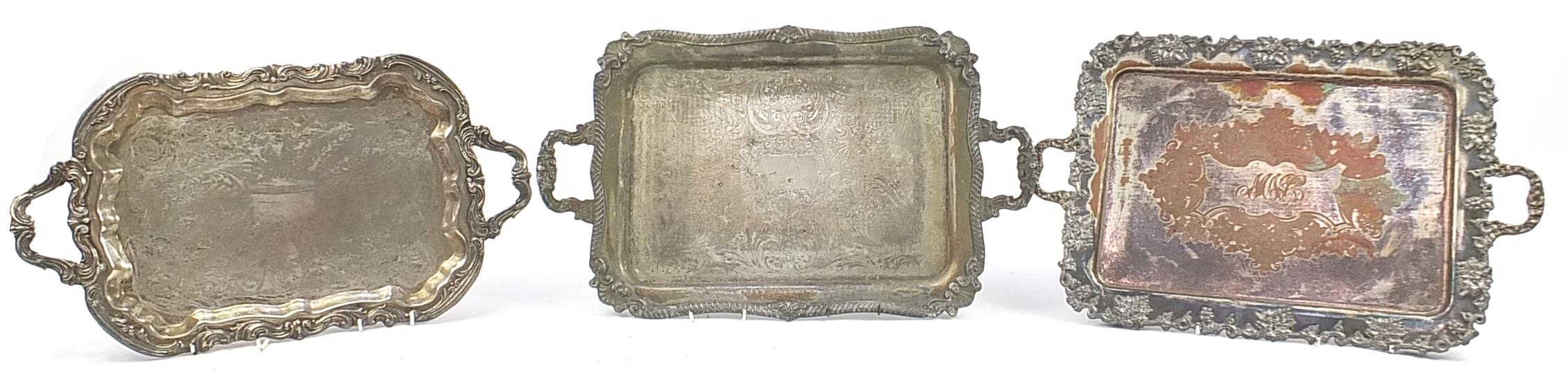 Three heavy silver plated trays with twin handles, the largest 68cm wide