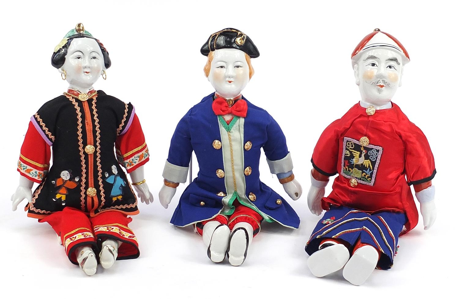 Three Chinese porcelain dolls with cloth bodies and tapestry clothing, the largest 41cm high
