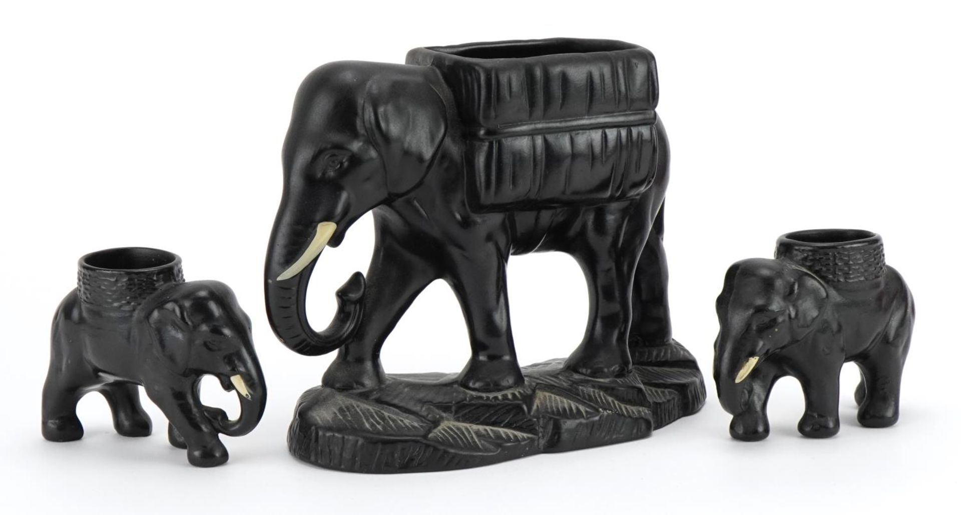 Three early 20th century black painted pottery lion design planters, the largest 21cm in length