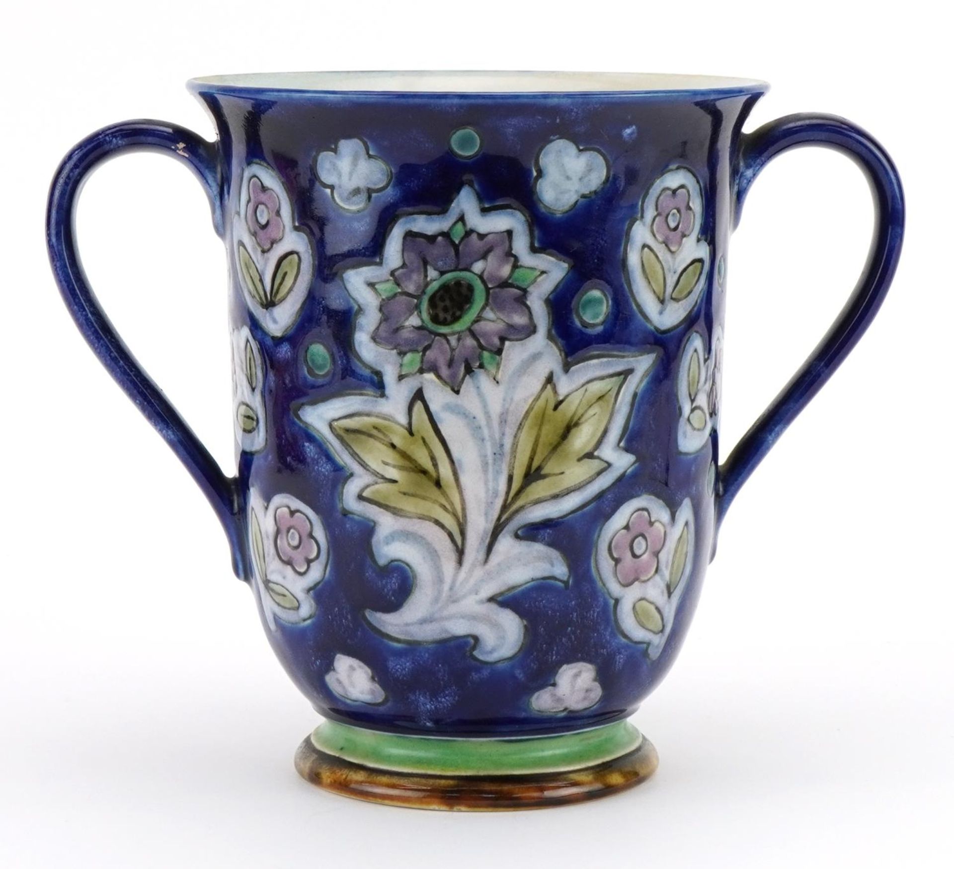 Doulton stoneware loving cup with twin handles hand painted with stylised flowers, 18.5cm high